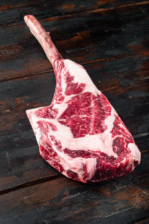 Tomahawk raw fresh beef steak with spices set, on old dark wooden table background, with copy space for textの写真素材