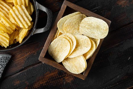 Crispy potato chips set, on old dark wooden table, top view flat lay