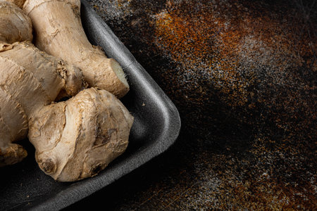 Fresh ginger root or rhizome set, in plastic market container, on old dark rustic background, with copy space for textの写真素材