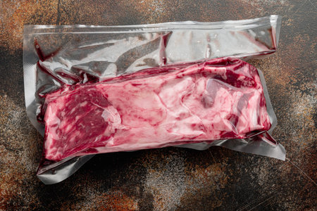 Raw rib eye beef meat steak cut in vacuum packaging set, on old dark rustic background, top view flat lay, with copy space for textの写真素材