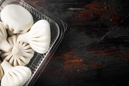 Frozen Raw dumplings Khinkali with beef and lamb meat set, in plastic tray, on old dark wooden table...