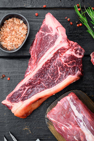 Fresh raw Prime Black Angus beef steaks set, T bone cut, on black wooden table, top view flat layの写真素材