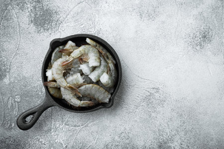 Black raw tiger shrimps set, in cast iron frying pan, on gray stone background, top view flat lay, with copy space for textの写真素材