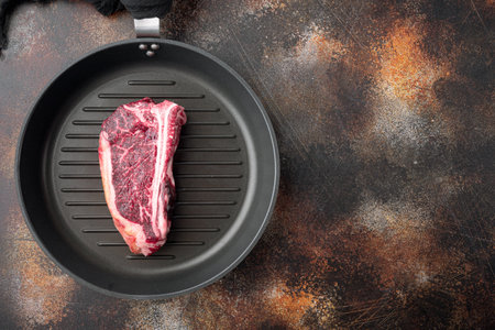 Dry aged club steak set, on frying cast iron pan, on old dark rustic background, top view flat lay, with copy space for textの写真素材