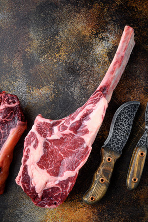 Cooking meat background. Raw tomahawk steak, with spices and herbs for cooking set, on old dark rustic background, top view flat lay, with copy space for textの写真素材