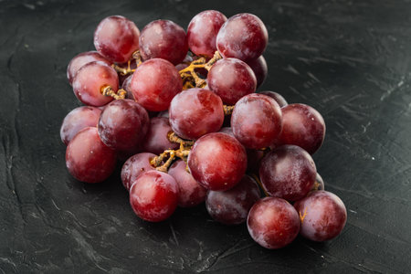 Red and white grapes set, dark red fruits, on black stone background