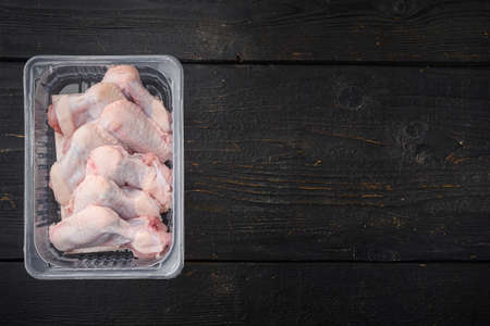 Raw chicken wings in plastic pack set, on black wooden table background, top view flat lay, with copy space for textの写真素材