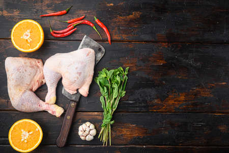 Organic chicken legs with spices and garlic set, with old butcher cleaver, on old dark wooden table, top view flat lay, with copy space for textの写真素材