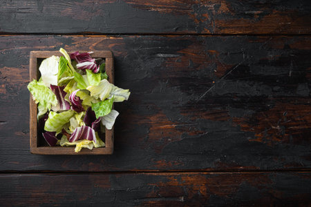 Mix fresh leaves of arugula, lettuce, spinach, beets for salad set, in wooden box, on old dark...