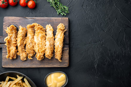 Crispy chicken sticks meat on black background, top view, with space for text.