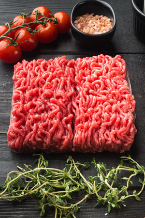 Minced meat mixture for meatballs and ingredients set, on black wooden table background