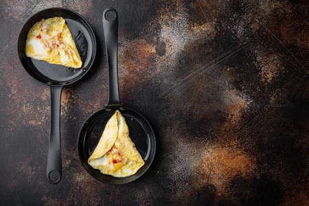 Spanish omelette, fresh red chili, brown and white crab meat, lemon, Cheddar cheese, eggs fried, on frying iron pan, on old dark rustic background, top view flat lay, with copy space and space for textの写真素材