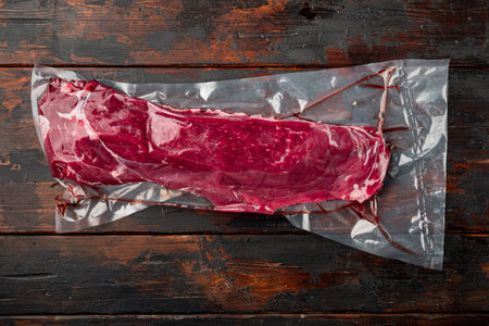Fillet beef vacuum bag for sous vide set, on old dark wooden table background, top view flat lay