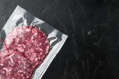 Vacuum beef cutlet sealed airtight pack set, on black stone background, top view flat lay, with copy space for textの写真素材