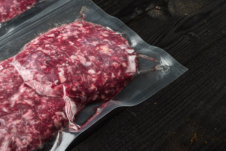 Vacuum beef cutlet sealed airtight pack set, on black wooden table background, with copy space for textの写真素材