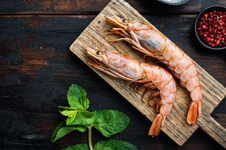 King prawns with herbs over dark rustic wooden background, flat lay with copy space, food photo.の写真素材