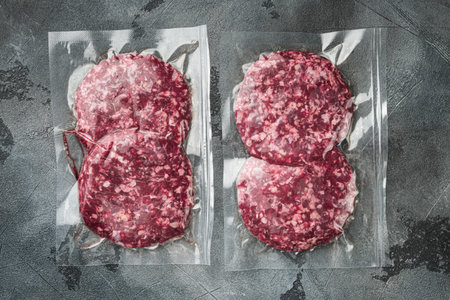 Burger meat vacuum sealed ready for sous vide cooking set, on gray stone background, top view flat...