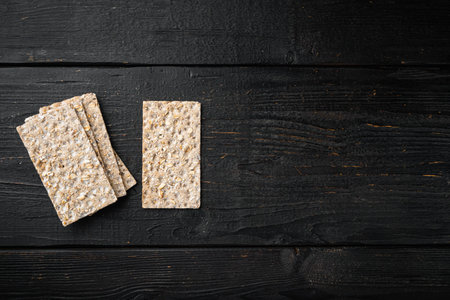 Crisp bread with sunflower, chia and sesames seeds set, on black wooden table background, top view...