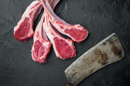 Fresh chopped calf Racks of lamb ready for cooking set, and old butcher cleaver knife, on black stone background, top view flat lay, with copyspace and space for textの写真素材