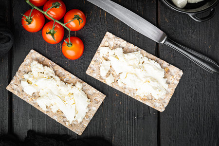 Wholegrain Rye Crispbread with cream cheese set, on black wooden table background, top view flat lay