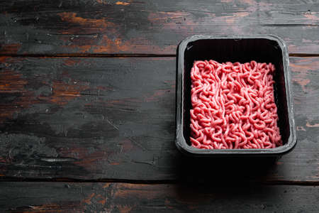 Fresh minced meat in plastic box packaging tray set, on old dark wooden table background, with copy space for textの写真素材