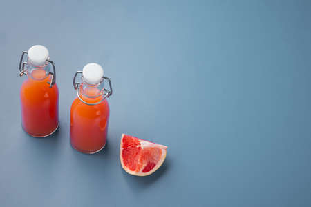 Fresh grapefruits and glass of grapefruit juice set, on blue textured summer background, with copy space for textの写真素材