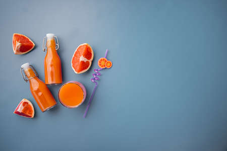 Fresh grapefruits and glass of grapefruit juice set, on blue textured summer background, top view flat lay, with copy space for textの写真素材