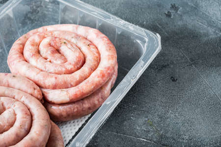 Raw spiral sausage set, on gray background, in plastic pack, with space for text copyspaceの写真素材