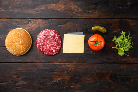 Homemade hamburger. Raw beef patties, sesame buns with other ingredients set, on old dark wooden table background, top view flat lay, with copy space for textの写真素材
