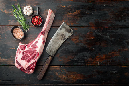 Raw tomahawk beef steak with ingredients for grilling with a spice rub set, and old butcher cleaver...