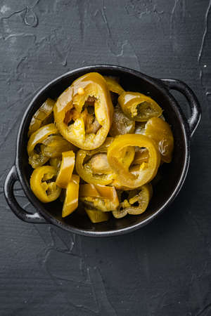 Green, organic pickled jalapenos in a bowl, on black background, top view flat layの写真素材