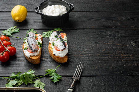 Crostini with fish and ricotta, on black wooden table background, with copy space for textの写真素材