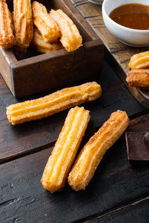 Tasty churros with chocolate caramel sauce set, on old dark wooden table backgroundの写真素材