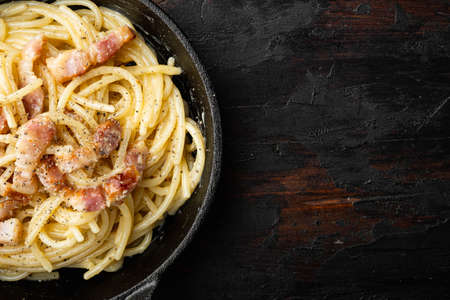 Carbonara pasta dish. Traditional Roman cuisine. Italian food set, in cast iron frying pan, on old dark wooden table, top view flat lay, with copy space for textの写真素材