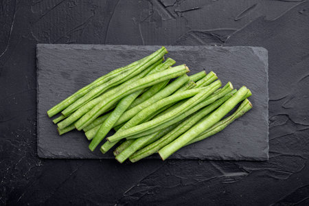 Green french beans cooking set, on stone board, on black background, top view flat lay
