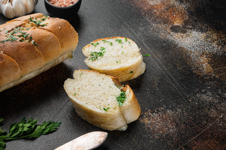 Sliced grilled bread with garlic and herbs set, on old dark rustic table background, with copy space...