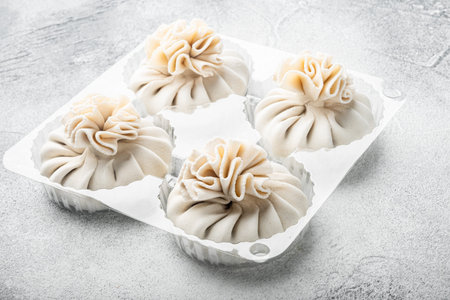 Homemade, traditional chinese pan fried dumplings set, in plastic tray, on gray stone background