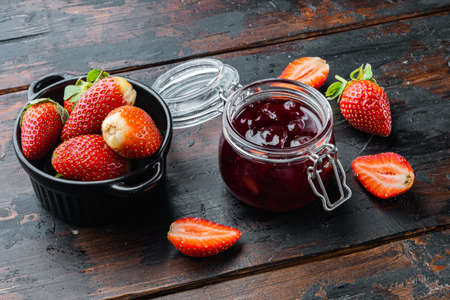 Homemade delicious strawberry jam and with fresh berrie, on old dark wooden table backgroundの写真素材