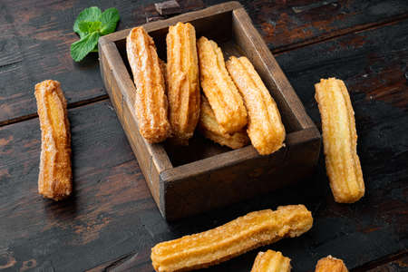 Churros with sugar, and chocolate sauce, on old dark wooden table backgroundの写真素材