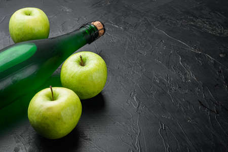 Fresh ripe apples and apple cider vinegar set, on black dark stone table background, with copy space for textの写真素材
