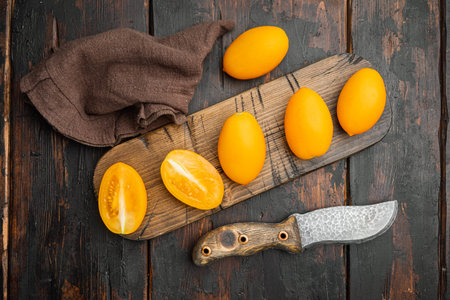 Yellow tomato set, on old dark wooden table background, top view flat lay