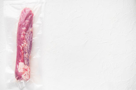 Vacuum packaging of meat products pork fillet tenderloin set, on white stone background, top view flat lay, with copyspace and space for textの写真素材