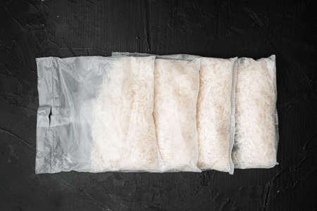 Rice in portion bags set, on black dark stone table background, top view flat layの写真素材