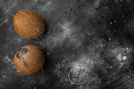 Whole ripe fresh Coconut set, on black dark stone table background, top view flat lay, with copy space for textの写真素材