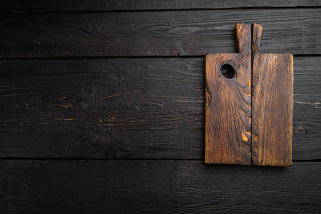 Old cutting board, top view flat lay , with copy space for text or food, on black wooden table backgroundの写真素材