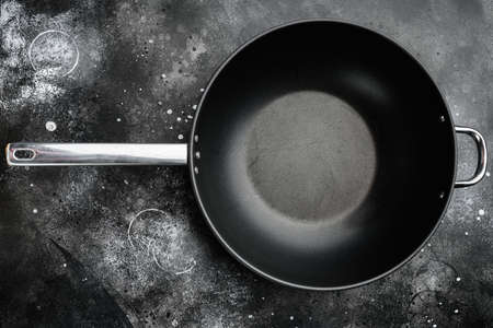 Wok pan empty with copy space for text or food with copy space for text or food, top view flat lay , on black dark stone table backgroundの写真素材