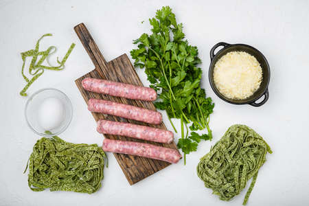 Fresh green pasta and sausages, on white stone table background, top view flat layの写真素材
