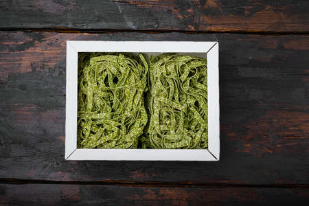 Raw green pasta pack, on old dark wooden table background, top view flat layの写真素材