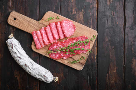 Salchichon sausages cut in slices on old wooden table, top view with copy space.の写真素材