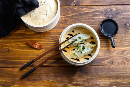 Chinese dumplings wooden steamer on wood background with soy and sticks. Traditional asian recipe. top viewの写真素材
